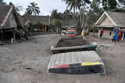 • People walk near trucks buried in volcanic ashes after Mount Semeru eruption in Lumgang