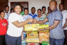 • Ms Watigi, (left) presenting the items to Mr Anderson. With them are members of the group and the students