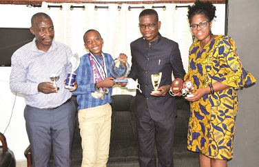 Young Philip presents his SWAG award and other medals to Mr Agbenu (Second right) while the parent look on