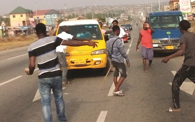 Some drivers with stone and stick preventing a colleague driver from working at Awoshie in Accra. Photo. Ebo Gorman