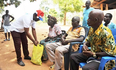 • Mr Afrifa (in white) presenting a parcel to a resident at Adukrom