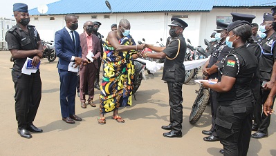 Daasebre Kwebu Ewusie VII (fourth from left) presenting the keys to the motorbikes to DCOP Bediako,with them are police personnel and officials of the company