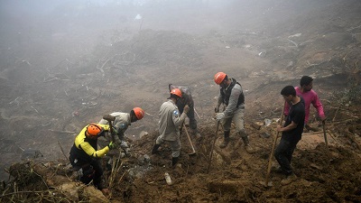 Workers dug with spades and shovels through the rubble and muck in a dense fog on Saturday