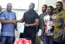 Mr Ayikwei (fourth right) hands over a copy of the contract to Mr Neequaye while Oko Nartey (third right) and others look on