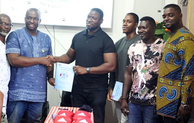 Mr Ayikwei (fourth right) hands over a copy of the contract to Mr Neequaye while Oko Nartey (third right) and others look on