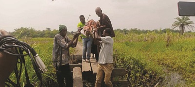 Some residents carrying a pregnant woman across the bridge to a health facility