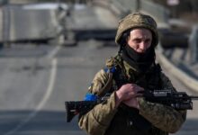 A Ukrainian soldier walks near a destroyed bridge in the Sumy region