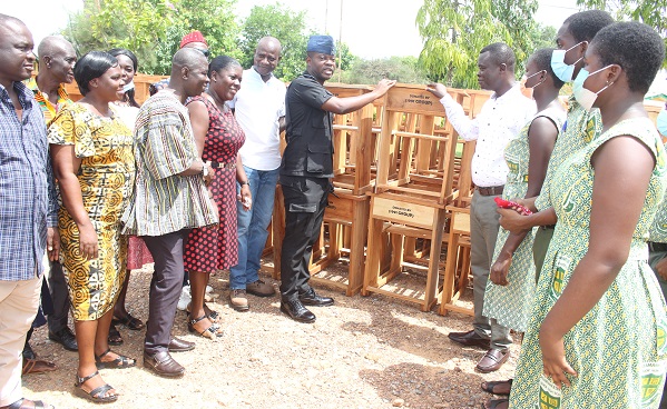 DSP John Akrofi Ansah (sixth from left) presenting the desks to Mr Benjamin Okai Sakyi,with them are members of the group and students