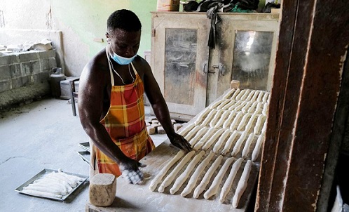 Mr Asante prepares rolls of bread dough to bake