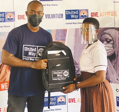 MrKissiedu presenting a school bag to one of the beneficiaries