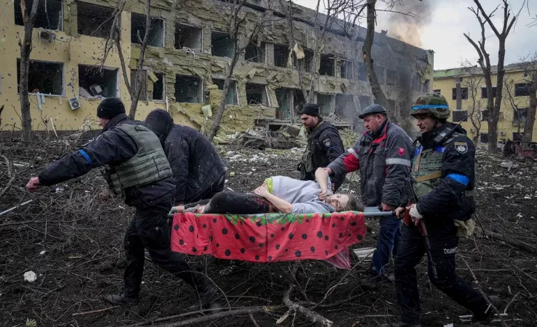 An injured pregnant woman is carried away from the damaged maternity hospital in Mariupol