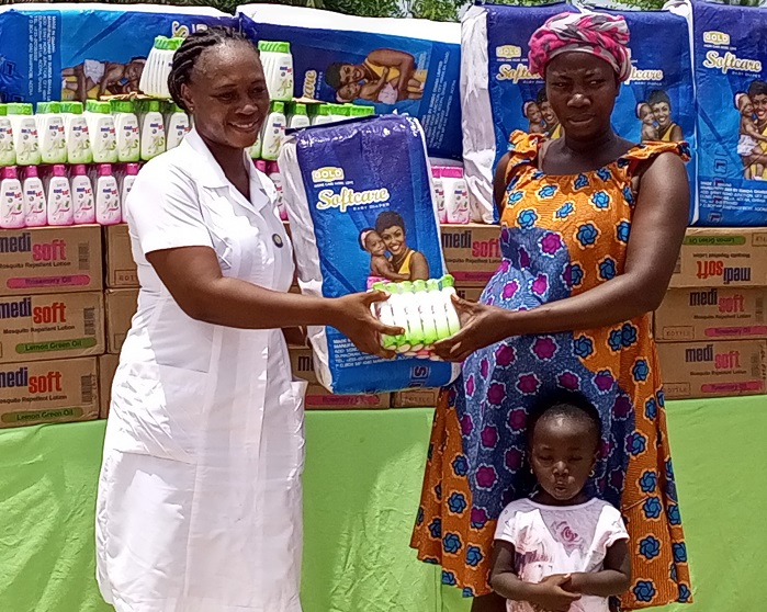 Ms Edith Arthur presenting a diaper to a pregnant woman at the ceremony