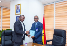 Mr Awuah exchanging a document with Dr Antwi-Boasiako