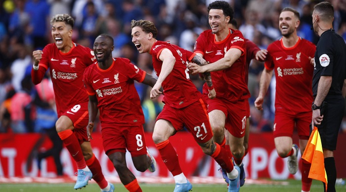 Liverpool players celebrate the victory with their hero, Tsimikas (middle)