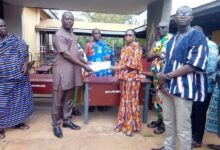 Mr Patrick Bannor (Left) handing over the furniture to Mrs Naomi Asantewaa (right) while Mr Anthony Mensah, DCE for Asutifi North looks on.