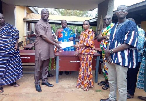 Mr Patrick Bannor (Left) handing over the furniture to Mrs Naomi Asantewaa (right) while Mr Anthony Mensah, DCE for Asutifi North looks on.