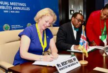 Ms Ford signing a document alongside Akinwumi Adesina, President of the AfDB
