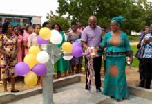 • Ms Babachuwey assisting a representative from the Ministries to cut a ribbon to officially inaugurate the borehole, looking on are students and staff of the school