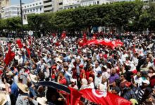 Demonstrators carry flags as they gather during a protest against President Saied in Tunis