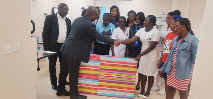Mr Okine (left) presenting the TV set to a nurse at the children’s ward while other staff of the ECG and hospital looks on