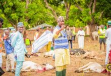 Alhaji Farouk Mahama (hand-stretched) standing by the slaughtered cows