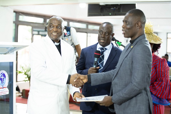 Reverend Emmanuel Teimah Barrigah (left) presenting a certificate to Apostle Immanuel Nii Okuley Tettey (right) behind them Reverend Paul Frimpong-Manso