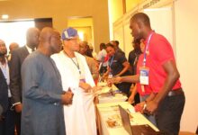 Dr Mustapha Abdul-Hamid (second from left) and Mr William Owuraku Aidoo (left) being briefed at the exhibition stand. Photo. Ebo Gorman