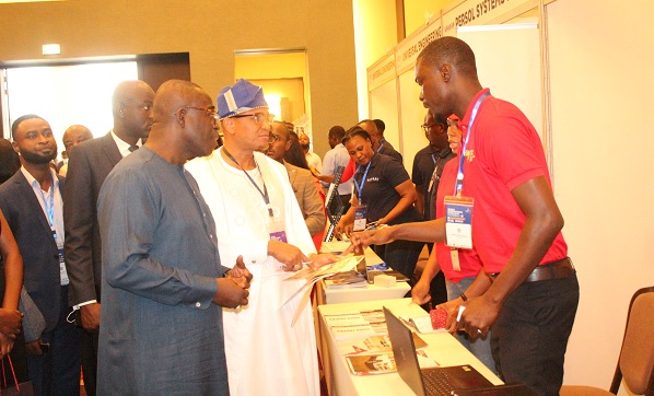 Dr Mustapha Abdul-Hamid (second from left) and Mr William Owuraku Aidoo (left) being briefed at the exhibition stand. Photo. Ebo Gorman