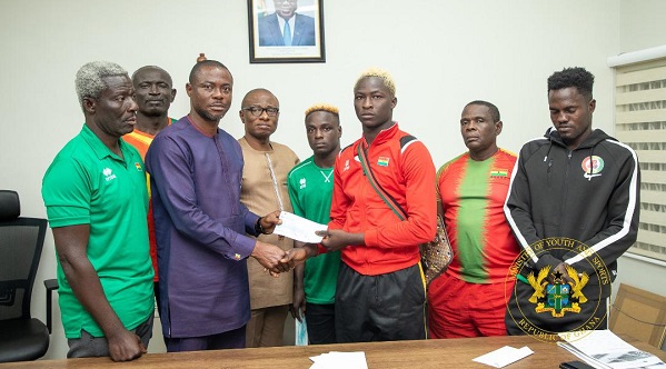 Deputy Minister of Youth and Sports Evans Opoku Bobie (second left) with the support of the Chief Accountant - Alhaji Osman Haruna Tweneboah (left) presenting the cheques to medal winners and coaches