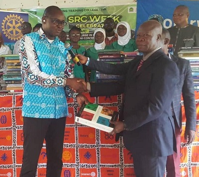 The president of the Wa Rotary Club Mr Stephen Mwinkaara (left) handing over the books the principal of the school