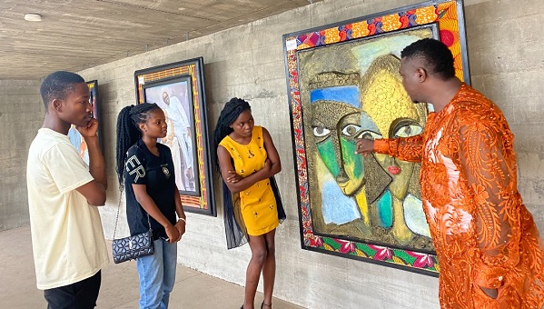 Mr Onochie (right) showing some patrons an artwork