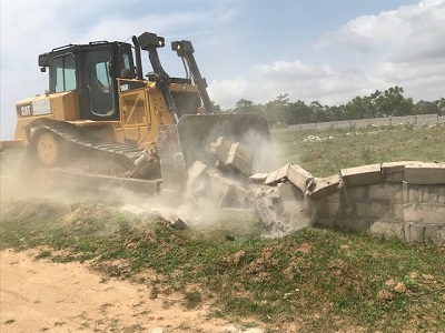 A bulldozer demolishing a fence wall at the site
