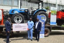 Mr Isaac Amissah Aidoo of GEIXM Bank(second from right) presenting the dummy cheque to Mr Yaw Frimpong Addo(left) at the background is the tractor with its trailor. Photo. Vincent Dzatse