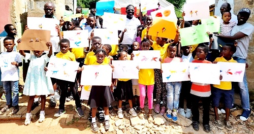 The pupils, volunteers and Founder of R and F foundation (middle), displaying their paintings