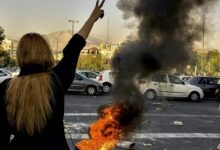 Protesters gathered near a burning vehicle in Karaj