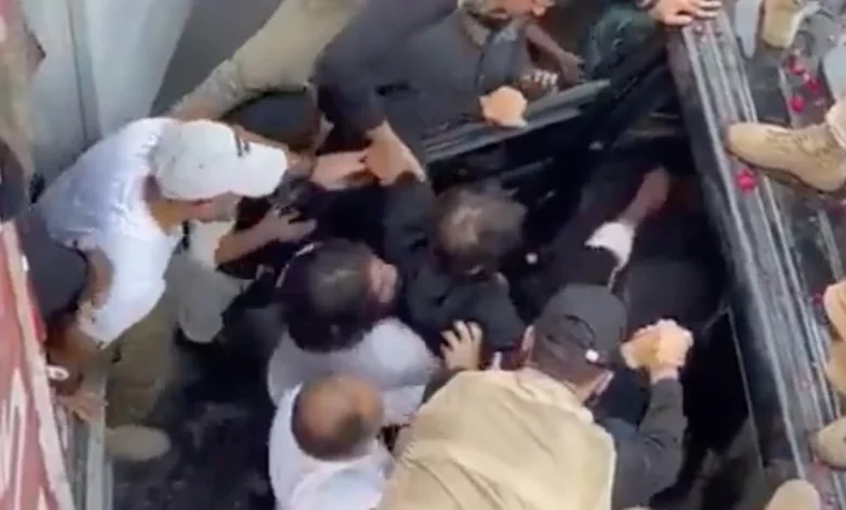 Imran Khan is carried into a car after being shot at a protest march