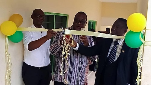 • Mr Abazing (right) cutting tape to open the classroom block (inset)