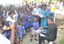 • Mr Abdourahamane Diallo (right) presenting a book to a pupil of Osu Presby Cluster of School Photo: Victor A. Buxton