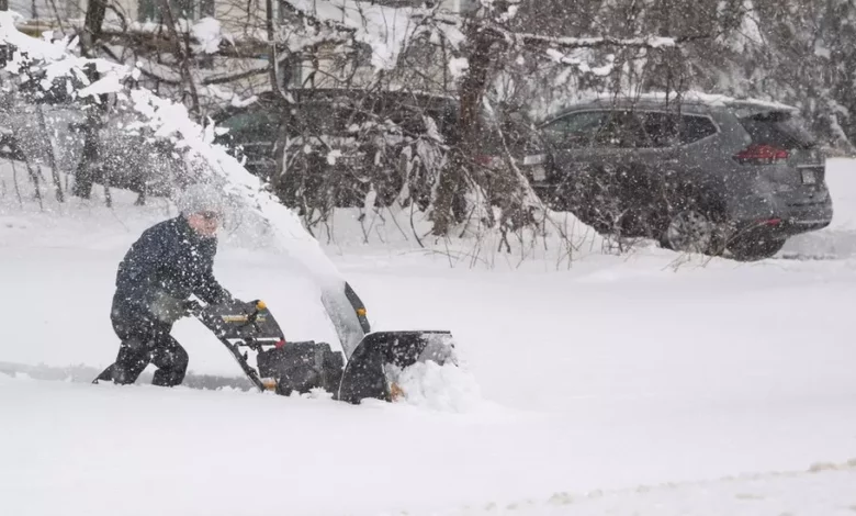 A person tries to clear snow from their driveway, over a foot deep, during a winter storm in Massachusetts