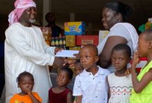 • Mr Ntiamoah (left) presenting the items to Ms Otemah, while the children look on