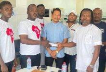 Mr Fuseini Twins (right) and a Brand Ambassador of RP Limited presenting the cash to one of the academy coaches as others looked on