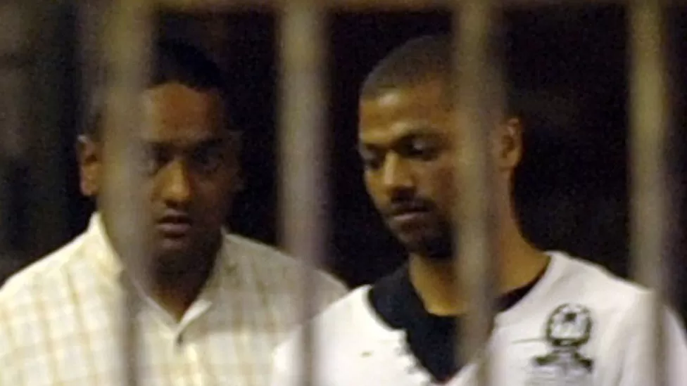 A police officer leads Thabo Bester (right) out of the holding cells at the Durban Magistrates Court in 2011