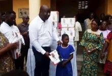 Dr Kissi presenting copy of the exercise book to a student