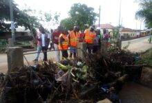 Mr Bossing and Ms Amewugah inspecting one of chocked gutters with refuse leading to flood at Ho- Bankoe