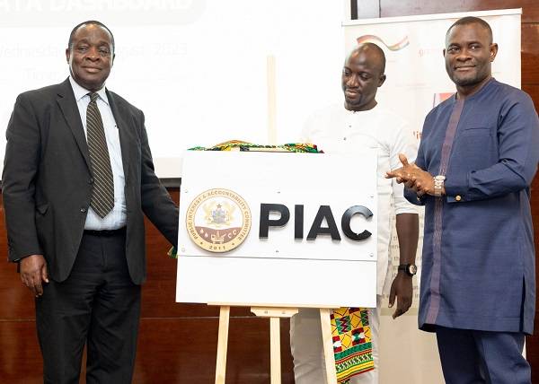 Mr John Kumah (right) being assisted by Mr Kwame Adom-Frimpong (left) to unveil the logo. With them is Mr Nasir Alfa Mohammed, PIAC Vice Chairman