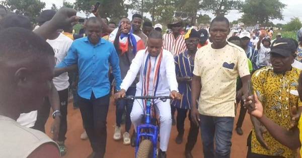 Mr Joseph Dindiok Kpemka (being flanked by his supporters) as he heads to the party's office on a bicycle to file his nomination forms