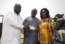 • Pastor Dorgbetor (left) receiving a cheque for the first sale of a copy of the book during the launch