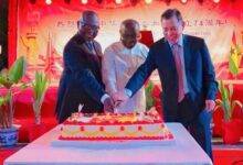 Mr Ken Ofori-Atta (middle) being assisted by Mr Lu (right) and Mr Asenso-Boakye to cutting the cake