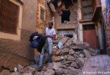 • Hussein Adnaie carries belongings out of his damaged house in Moulay Brahim