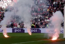 Fire flares on the pitch during the game .